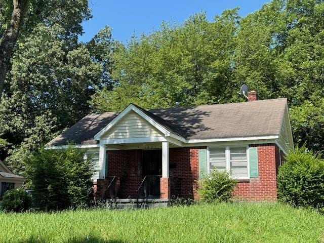 1827 S Orleans Ave, Memphis, TN 38106 - view of front of home featuring brick siding, a chimney, and a porch