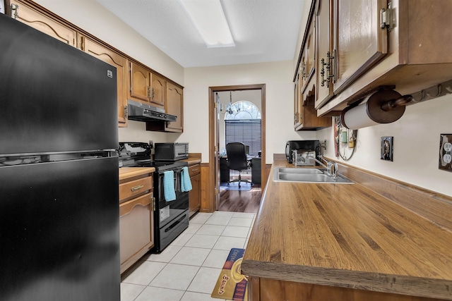 4532 Quail Flight Cv, Memphis, TN 38141 - kitchen with black appliances, under cabinet range hood, light tile patterned flooring, a desk, and brown cabinetry