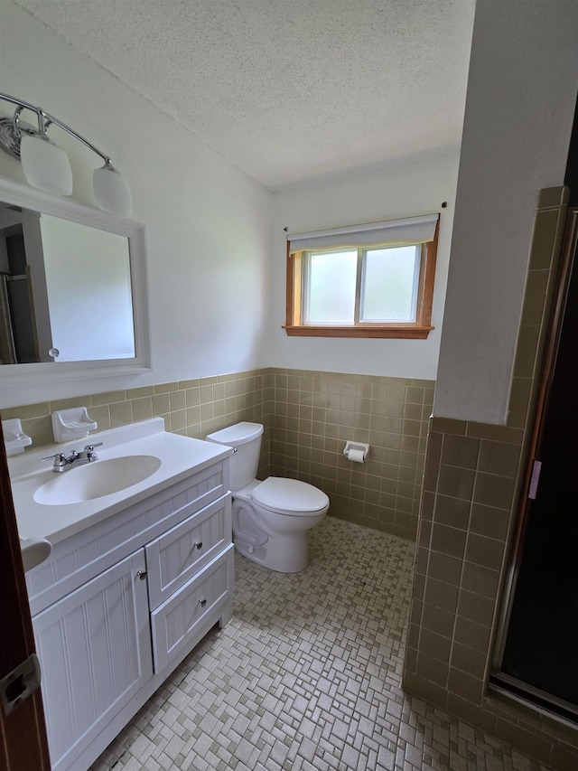 8355 Craven Rd, Bartlett, TN 38002 - full bath featuring tile walls, a textured ceiling, vanity, wainscoting, and a shower with shower door