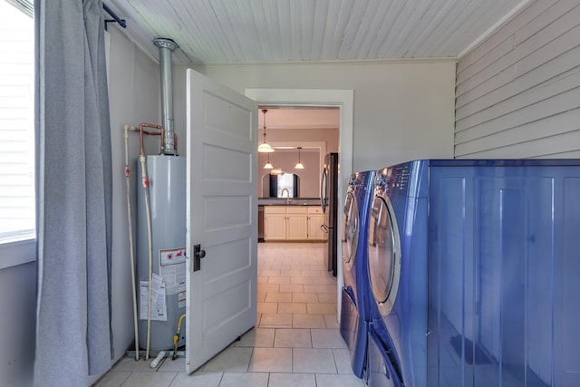 699 New York St, Memphis, TN 38104 - laundry room featuring water heater, washer and dryer, light tile patterned floors, and wood walls