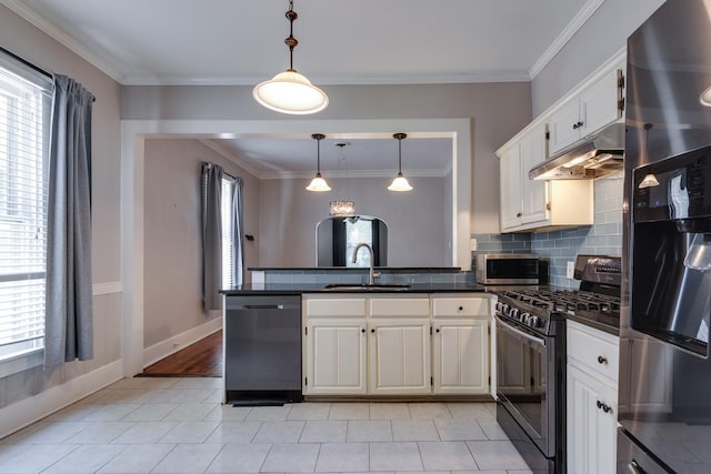 699 New York St, Memphis, TN 38104 - kitchen with appliances with stainless steel finishes, a peninsula, dark countertops, under cabinet range hood, and white cabinetry