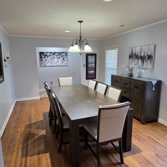 6380 Davidson Cv, Memphis, TN 38119 - dining space featuring light wood finished floors, ornamental molding, a textured ceiling, and a chandelier