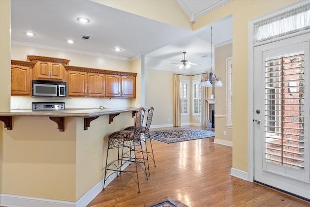536 Warwick Willow Ln, Collierville, TN 38017 - kitchen featuring stainless steel microwave, a breakfast bar, ornamental molding, light wood-style floors, and stove