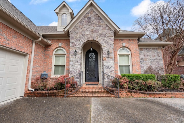 536 Warwick Willow Ln, Collierville, TN 38017 - doorway to property featuring stone siding, an attached garage, and a shingled roof