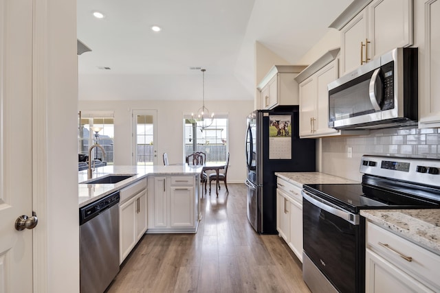 50 Misty Meadow Ln, Oakland, TN 38060 - kitchen with appliances with stainless steel finishes, a chandelier, light wood-style flooring, backsplash, and light stone countertops
