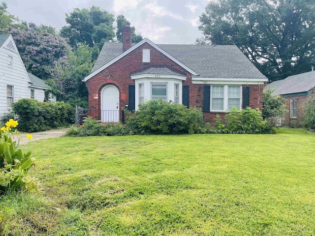 990 N Avalon St, Memphis, TN 38107 - tudor house featuring brick siding, a chimney, a front lawn, and a shingled roof