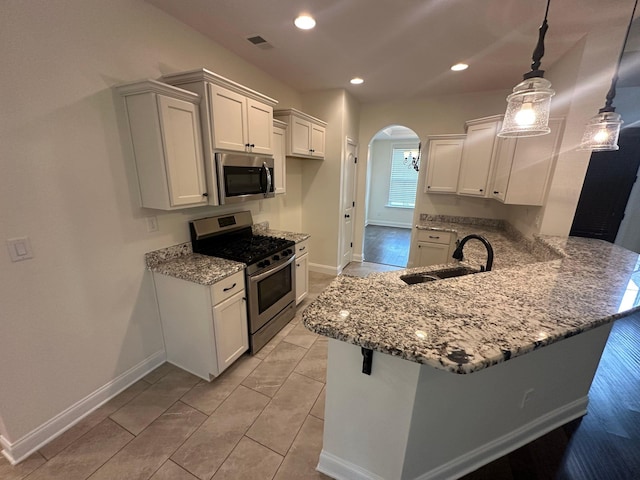 4689 Riva Ridge Dr, Olive Branch, MS 38654 - kitchen with appliances with stainless steel finishes, arched walkways, light stone counters, a peninsula, and white cabinetry