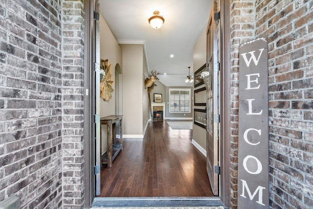 70 Shady Pine Cv, Oakland, TN 38060 - entryway with wood-type flooring, a lit fireplace, brick wall, a ceiling fan, and arched walkways