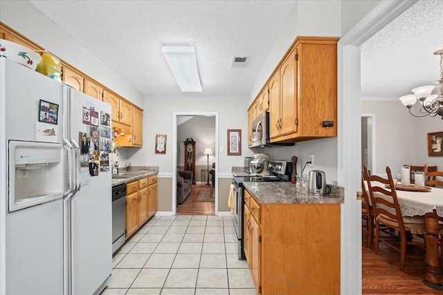 6445 Baird Ln, Bartlett, TN 38135 - kitchen featuring appliances with stainless steel finishes, a textured ceiling, a chandelier, and light tile patterned flooring