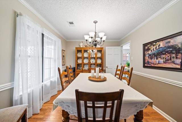 6445 Baird Ln, Bartlett, TN 38135 - dining space featuring a chandelier, a textured ceiling, crown molding, and light wood-style floors