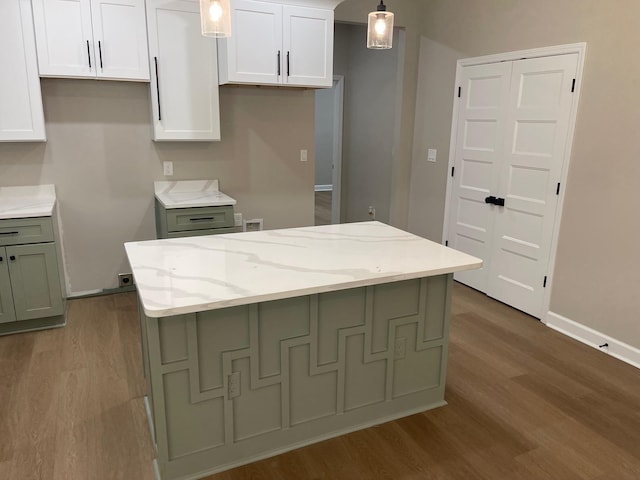 1998 Cloverdale Dr, Memphis, TN 38114 - kitchen with wood finished floors, light stone countertops, white cabinets, a kitchen island, and decorative light fixtures