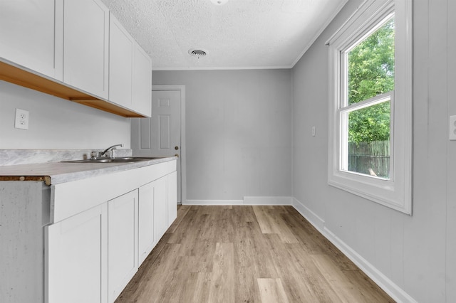 849 Restbrook Ave, Memphis, TN 38127 - kitchen with light wood-style flooring, a textured ceiling, white cabinets, light countertops, and ornamental molding