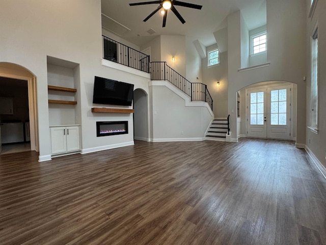 7412 Lost Trail Dr, Cordova, TN 38016 - unfurnished living room featuring a towering ceiling, ceiling fan, a glass covered fireplace, dark wood-type flooring, and arched walkways