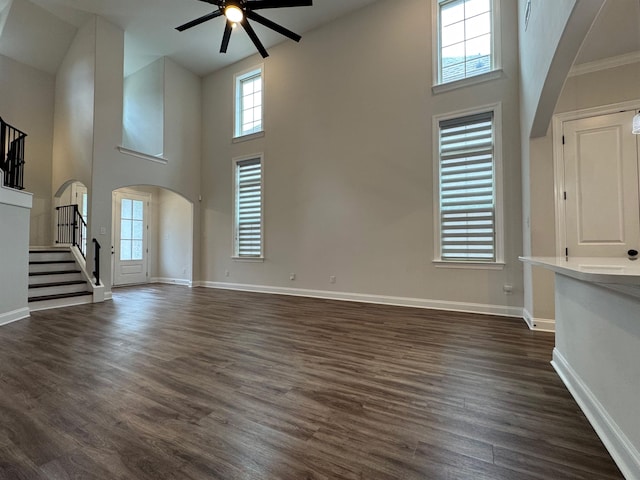 7412 Lost Trail Dr, Cordova, TN 38016 - unfurnished living room with arched walkways, a ceiling fan, high vaulted ceiling, stairway, and dark wood-style flooring
