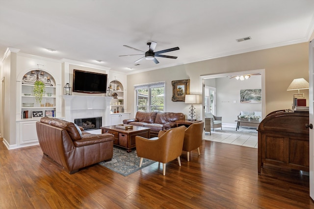 927 Oakmont Ridge Cv, Collierville, TN 38017 - living room featuring ceiling fan, wood finished floors, a tiled fireplace, crown molding, and built in features