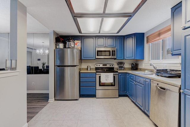 4764 Eagle Crest Dr Unit 4002, Memphis, TN 38117 - kitchen featuring stainless steel appliances, blue cabinets, a chandelier, light countertops, and light tile patterned floors