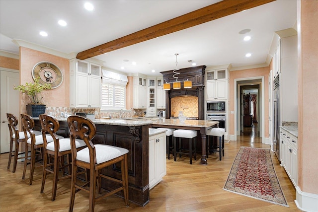 269 N Monterey Farms Cv, Collierville, TN 38017 - kitchen with ornamental molding, a breakfast bar, built in microwave, backsplash, and light wood finished floors