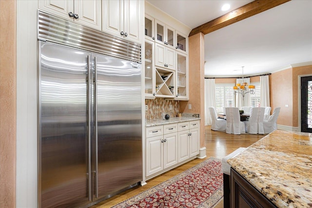 269 N Monterey Farms Cv, Collierville, TN 38017 - kitchen featuring built in fridge, a chandelier, light wood-type flooring, glass insert cabinets, and light stone counters