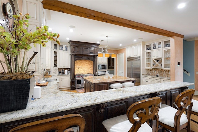 269 N Monterey Farms Cv, Collierville, TN 38017 - kitchen featuring built in appliances, backsplash, light stone counters, recessed lighting, and a peninsula