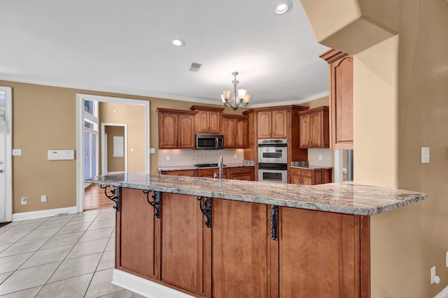 1062 Center Ridge Rd, Collierville, TN 38017 - kitchen featuring appliances with stainless steel finishes, a chandelier, brown cabinets, tasteful backsplash, and ornamental molding