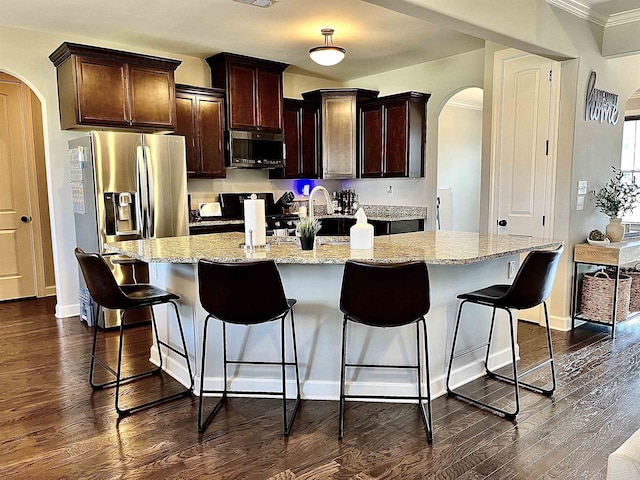 8334 Stonecrest Dr W, Olive Branch, MS 38654 - kitchen featuring arched walkways, appliances with stainless steel finishes, dark wood-style flooring, light stone counters, and crown molding
