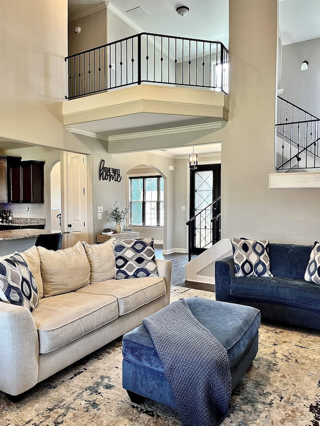 8334 Stonecrest Dr W, Olive Branch, MS 38654 - living room featuring arched walkways, a towering ceiling, stairway, and crown molding