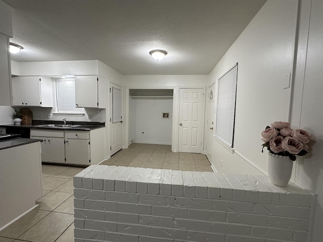 1289 Heathcliff Dr, Memphis, TN 38134 - kitchen featuring light tile patterned floors, a textured ceiling, dark countertops, and white cabinetry