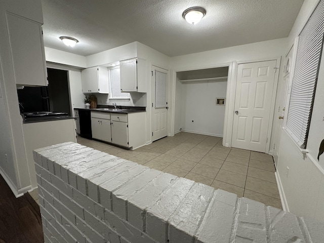 1289 Heathcliff Dr, Memphis, TN 38134 - kitchen featuring a textured ceiling, light tile patterned floors, white cabinets, dark countertops, and black dishwasher