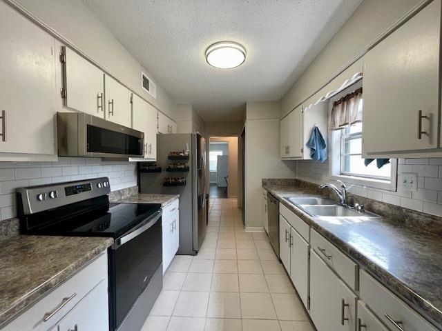 2470 S Flowering Tree Cv, Bartlett, TN 38134 - kitchen featuring stainless steel appliances, light tile patterned floors, backsplash, dark countertops, and a textured ceiling
