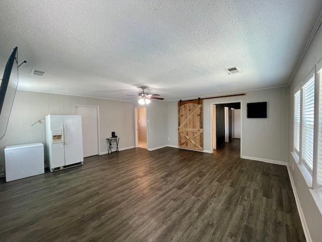 2470 S Flowering Tree Cv, Bartlett, TN 38134 - unfurnished living room featuring a textured ceiling, dark wood-style floors, a ceiling fan, and a barn door