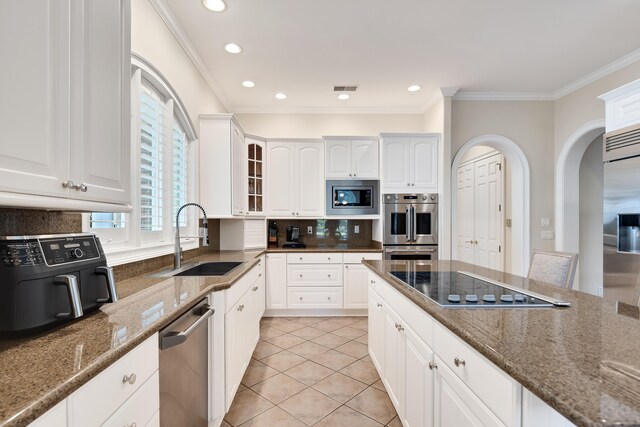 1426 Le Fleur Pl, Memphis, TN 38120 - kitchen featuring built in appliances, dark stone countertops, ornamental molding, glass insert cabinets, and tasteful backsplash