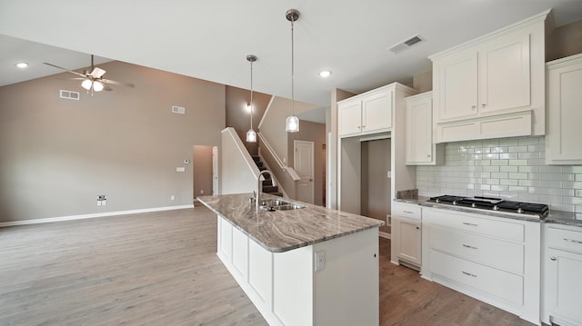 131 Pritchett Cv, Munford, TN 38058 - kitchen with ceiling fan, stainless steel gas cooktop, backsplash, light wood finished floors, and stone counters