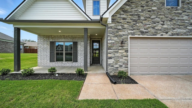 131 Pritchett Cv, Munford, TN 38058 - view of exterior entry with a yard, covered porch, concrete driveway, brick siding, and stone siding