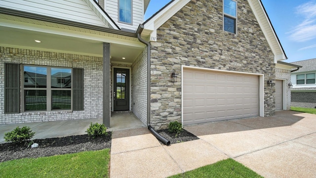131 Pritchett Cv, Munford, TN 38058 - view of exterior entry with concrete driveway, stone siding, and covered porch