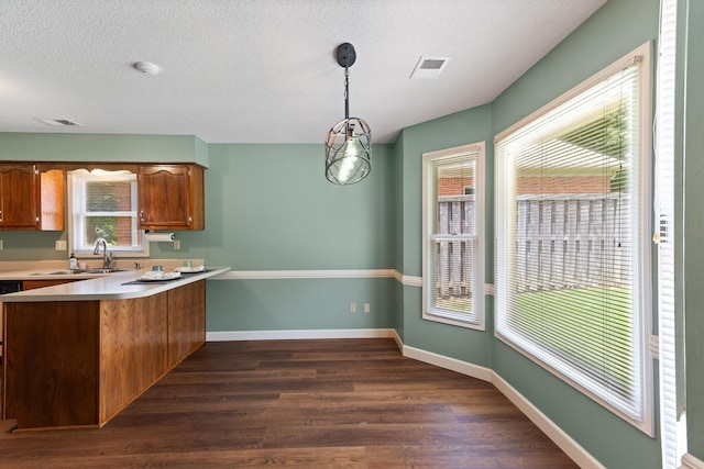 1504 Teal Wing Ln, Memphis, TN 38016 - kitchen with a peninsula, dark wood-type flooring, light countertops, brown cabinets, and a textured ceiling