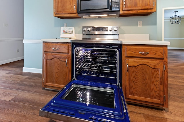 1504 Teal Wing Ln, Memphis, TN 38016 - kitchen with black microwave, stainless steel range with electric stovetop, dark wood-style flooring, light countertops, and brown cabinetry