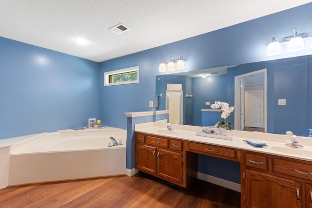 1504 Teal Wing Ln, Memphis, TN 38016 - full bathroom with wood finished floors, double vanity, a bath, and a textured ceiling