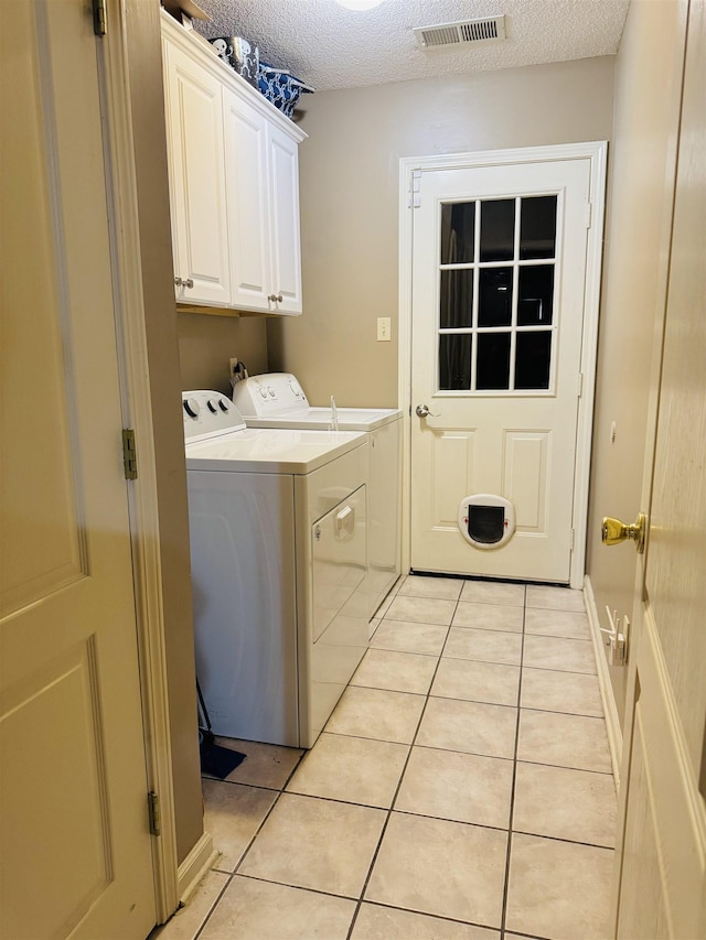 902 Wildbird Cv, Collierville, TN 38017 - laundry room featuring washing machine and clothes dryer, light tile patterned flooring, cabinet space, and a textured ceiling