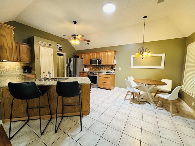 902 Wildbird Cv, Collierville, TN 38017 - kitchen with lofted ceiling, stainless steel appliances, a peninsula, tasteful backsplash, and light tile patterned floors
