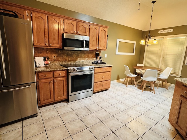 902 Wildbird Cv, Collierville, TN 38017 - kitchen featuring stainless steel appliances, tasteful backsplash, brown cabinetry, lofted ceiling, and hanging light fixtures