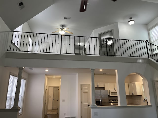 1319 E Island Pl E, Memphis, TN 38103 - unfurnished living room with a ceiling fan, a high ceiling, decorative columns, arched walkways, and stairs