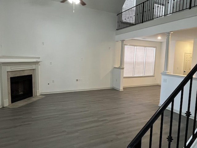 1319 E Island Pl E, Memphis, TN 38103 - unfurnished living room featuring wood finished floors, a ceiling fan, ornate columns, a tile fireplace, and stairway