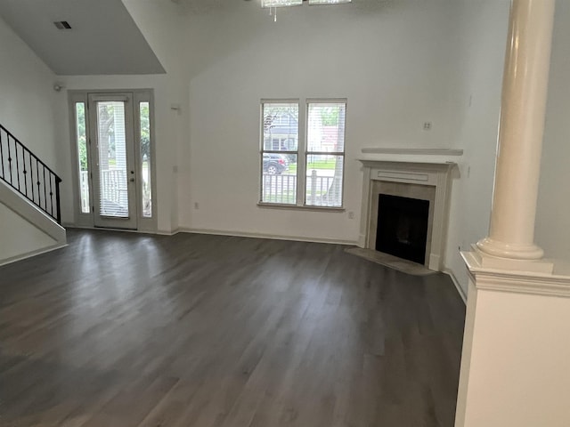 1319 E Island Pl E, Memphis, TN 38103 - unfurnished living room featuring dark wood-type flooring, a high end fireplace, stairs, lofted ceiling, and ornate columns