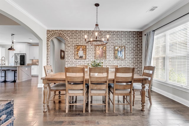 4712 Carousel Ln, Collierville, TN 38017 - dining space with healthy amount of natural light, dark wood-style floors, crown molding, brick wall, and a chandelier