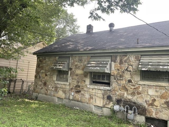 827 E Mallory Ave E, Memphis, TN 38106 - view of home's exterior featuring stone siding, a chimney, and a shingled roof