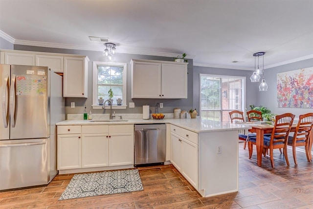 8973 E Carrollwood Ln, Memphis, TN 38016 - kitchen with appliances with stainless steel finishes, a peninsula, crown molding, light countertops, and hanging light fixtures