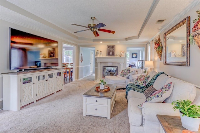 8973 E Carrollwood Ln, Memphis, TN 38016 - living area featuring light colored carpet, ceiling fan, a tiled fireplace, a raised ceiling, and a textured ceiling