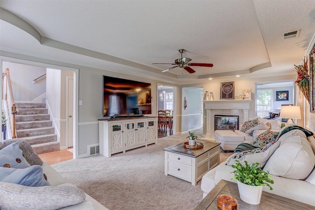 8973 E Carrollwood Ln, Memphis, TN 38016 - living room featuring a tray ceiling, a textured ceiling, ceiling fan, stairway, and a tile fireplace