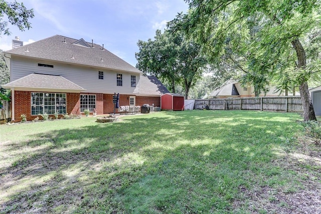 8973 E Carrollwood Ln, Memphis, TN 38016 - rear view of house with a storage unit, a fenced backyard, a fire pit, brick siding, and a chimney