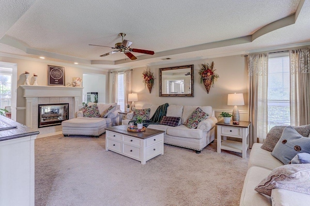 8973 E Carrollwood Ln, Memphis, TN 38016 - living room with a raised ceiling, light carpet, a ceiling fan, a textured ceiling, and a tile fireplace